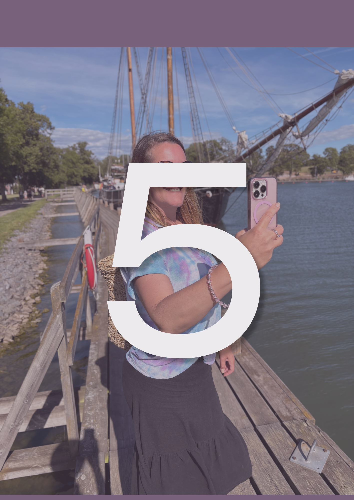 En kvinna som står ute på en brygga och håller upp sin telefon för att filma 